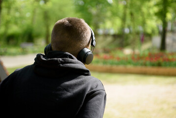 A young guy in headphones listens to music in nature. Poland, Zielona Gora