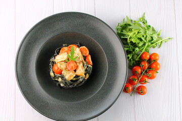 Black spaghetti. Black seafood pasta in white plate on black background with copy space.