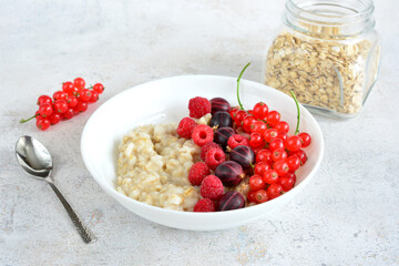 a bowl of oatmeal with raspberries, red currant and gooseberries