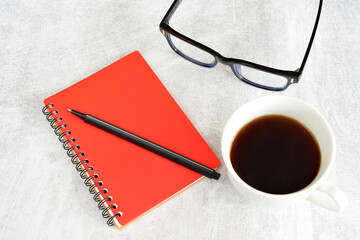 a notebook with a pen and glasses on a table 