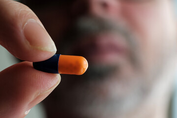 Close-up of fingers holding medicine capsule.