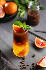 Coffee with orange juice (bumble) in a tall glass with ice and mint on a dark background