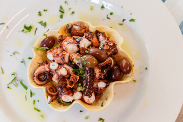 Tasty grilled octopus with potato and olive on a table in restaurant. Top view