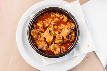 Stewed chicken gizzards in a sauce in a bowl on the table. Top view. Typical Spanish appetizer