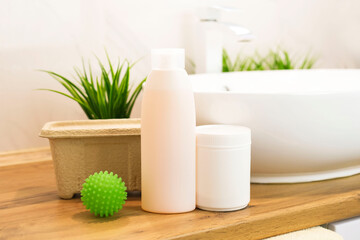 Various types of chemicals for washing clothes on wooden table overlooking modern bathroom. Washing powder, detergent. Concept of order and cleanliness in house.