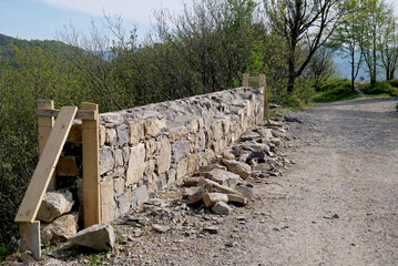 Reconstruction of a stone and concrete wall along an old military country road
