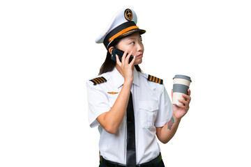 Airplane pilot Asian woman over isolated background holding coffee to take away and a mobile