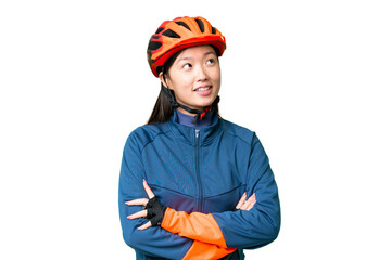 Young cyclist woman over isolated chroma key background looking up while smiling
