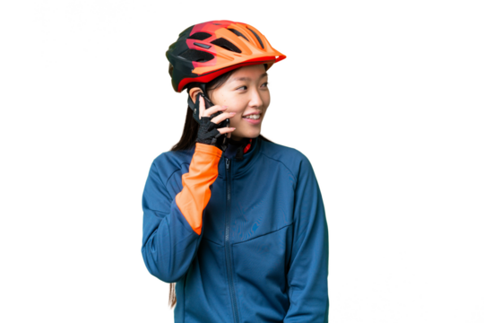 Young cyclist woman over isolated chroma key background keeping a conversation with the mobile phone with someone