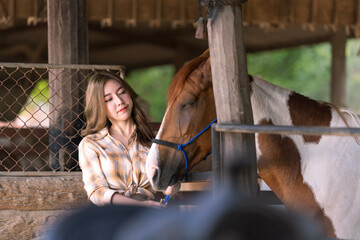Female farmer who is feeding beasts at the horse farm. Beautiful girl taking care of stallion. Female and beautiful horse.