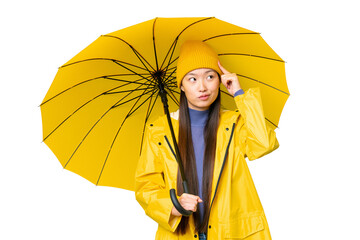 Young Asian woman with rainproof coat and umbrella over isolated chroma key background having...