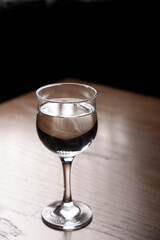 Glass of water on a wooden table. Selective focus. Toned.