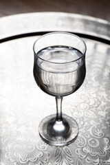 Glass of water on a wooden table. Selective focus. Toned.