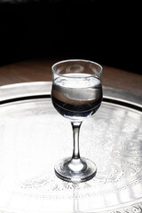 Glass of water on a wooden table. Selective focus. Toned.