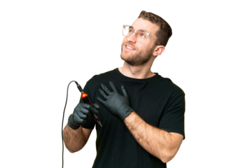 Tattoo artist man over isolated chroma key background looking up while smiling