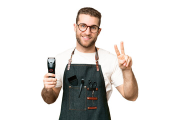 Barber man in an apron over isolated chroma key background smiling and showing victory sign