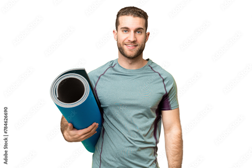 Wall mural Young sport man going to yoga classes while holding a mat over isolated chroma key background smiling a lot