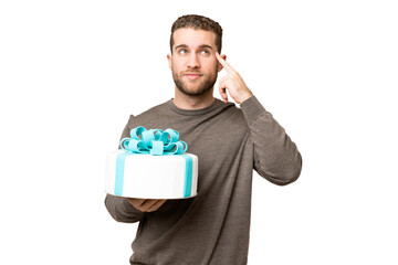 Young handsome blonde man holding birthday cake over isolated chroma key background having doubts...