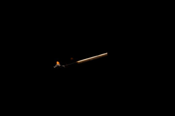 Lit falling match on a black background.