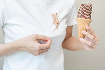 Cloth stain, disappointment asian young woman, girl eating melting ice cream in waffle cone on hot...
