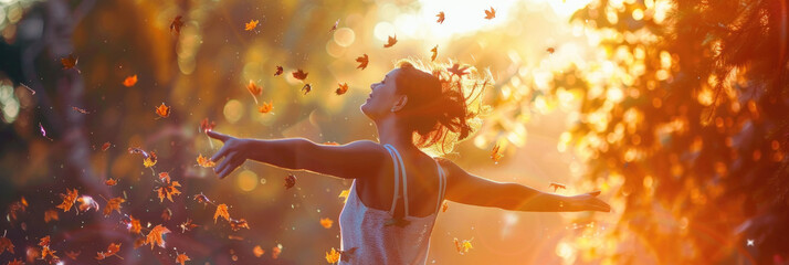 A woman with outstretched arms enjoys the warm glow of sunset among falling autumn leaves in a forest
