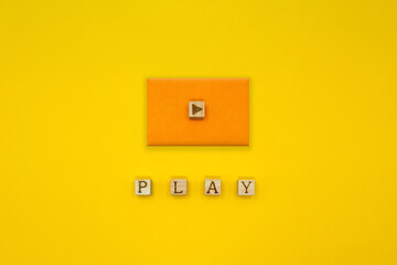 PLAYの単語の上にオレンジの四角い立体的な再生マークのアイコンが並ぶ黄色い背景 - obrazy, fototapety, plakaty