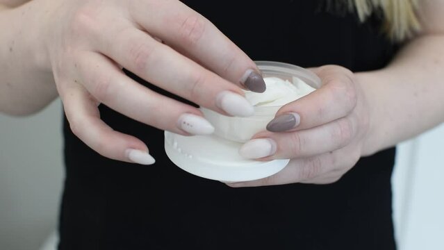 A  girl opens a box of snus and takes one bag.