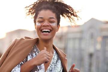 Outdoor portrait of happy joyful african american woman with shiny glitter on her face
