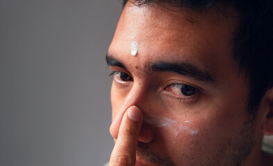 close-up of latin man applying cream to his face