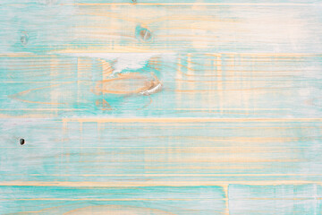 View of weathered wood on turquoise planks with visible grain giving worn stripped feel