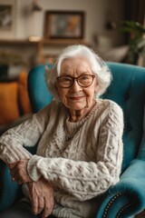 A comfortable, relaxed elderly woman, a grandmother, is sitting in an armchair, and looking at the camera in the living room.