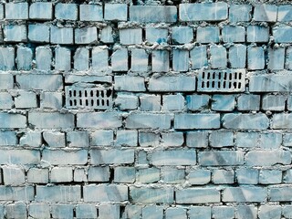 Old brick wall painted with blue and white paint.