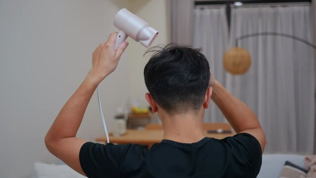 Asian man use of hairdryer after shower at home