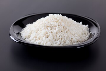 A black plate with white rice on a black background. Close-up