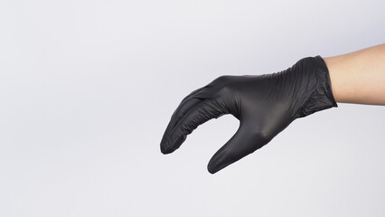 The hand is wearing a black latex glove and do hold or grab hand sign on white background.