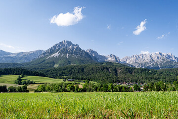 Österreiche Alpen in Tirol - das Hochgebirge des Wilden Kaisers mit grünen Wiesen und Feldern im Vordergrund.