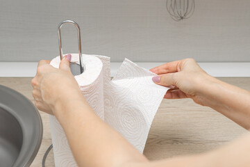 housewife in the kitchen tears off a paper towel.