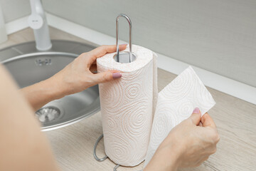 housewife in the kitchen tears off a paper towel, close-up
