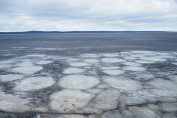 Ice drift in spring on Lake Onega, Karelia. Dangerous thin spring ice in April. Aggregate accumulations of fine-crystalline grains. Opening of small lakes, ponds and reservoirs. Crushed ice floes - obrazy, fototapety, plakaty