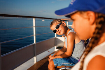 A boy wearing sunglasses and a blue cap relaxes on a boat with a girl, enjoying a sunny day on the...