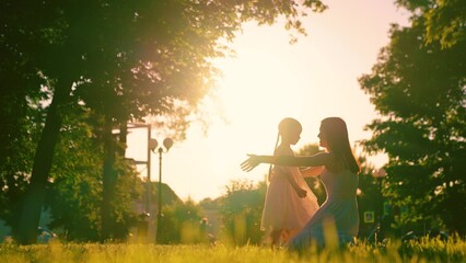 Family, Mom kid girl embrace, sun day. Carefree childhood, joyful embrace of child of mother. Child, daughter runs to mom, hugs her in park. Happy family. Child has fun in summer on street with mother