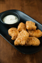 Nuggets with sour cream on wooden table, vertical frame