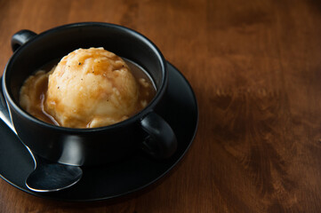 Mashed potato in black cup with spoon on wooden table