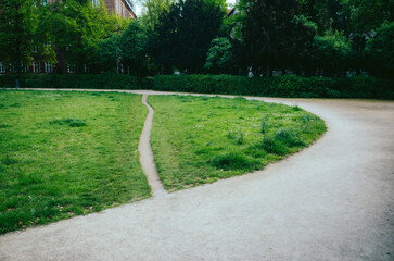 Desire Path in Park - A worn grass desire path splits off from a main gravel walkway in a verdant...