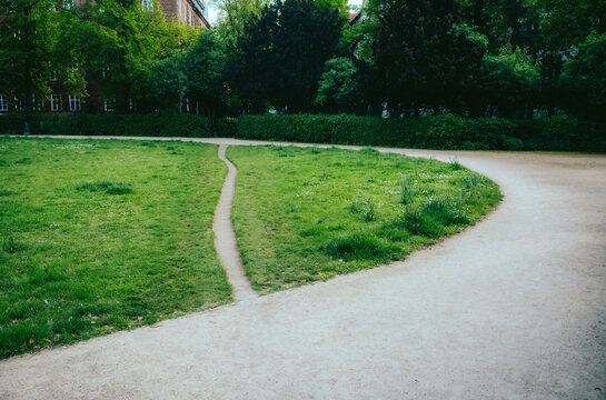 Desire Path in Park - A worn grass desire path splits off from a main gravel walkway in a verdant urban park, offering a shortcut through the greenery at Heidelberger Platz Berlin