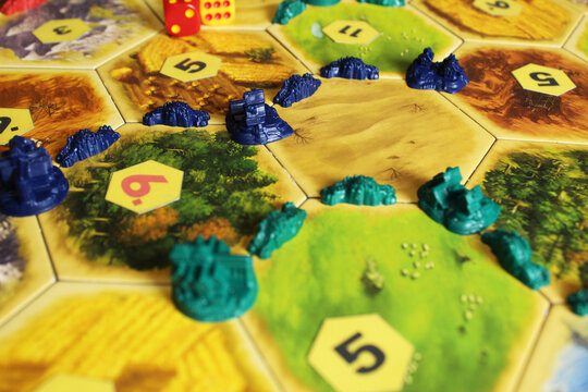 Mozyr, Belarus, April 01 2024: A catan board game green and blue chips of players on the field. Rivalry for hexes and resources between players. Cities and settlements in the game