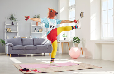 Funny man in retro sportswear and an amusing horse mask, doing stretching sport exercise with...