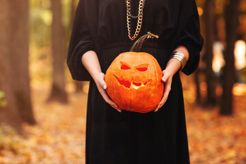 Young witch with jack o lantern in forest