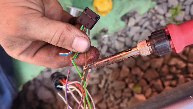 The technician soldering frayed wires on a car and insulating them with heat shrink tubing. Auto electrician repairing the wiring of a car at an auto service.