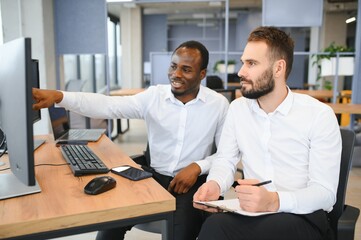 Two confident businessmen, financial analysts or investment advisers sitting at office desk
